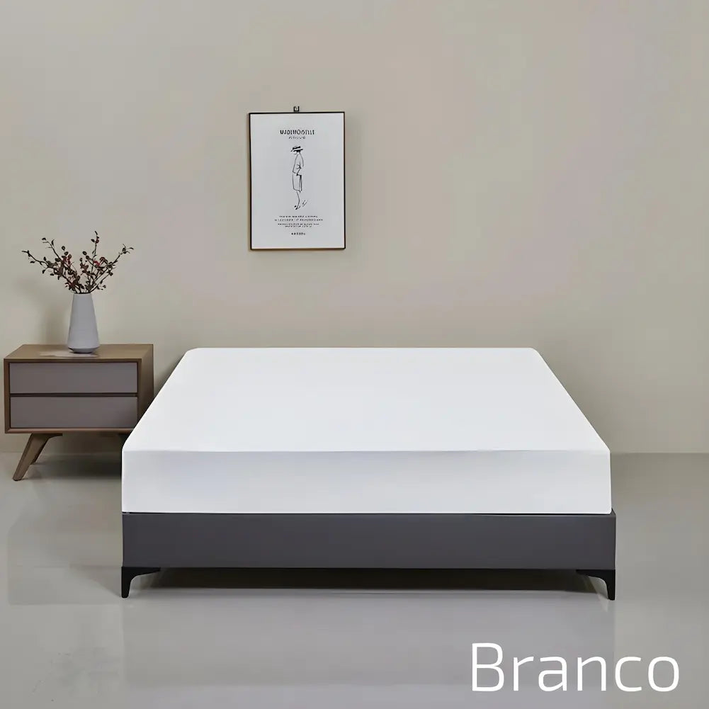 Imagem de uma cama com uma capa branca ajustada sobre o colchão, com base cinza escura. O fundo é uma parede bege com um quadro minimalista pendurado. Ao lado da cama, um criado-mudo de madeira com um vaso cinza com ramos secos. O texto no canto inferior direito diz "Branco".